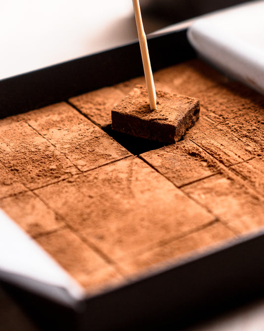 Ganache de Luxe – a cocoa-dusted ganache square lifted from the box on a wooden pick