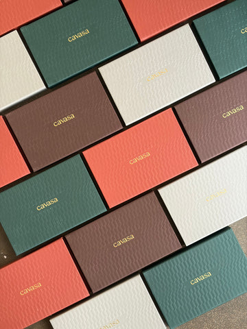 Cavasa textured gift boxes in coral, green, ivory and brown laid out in rows
